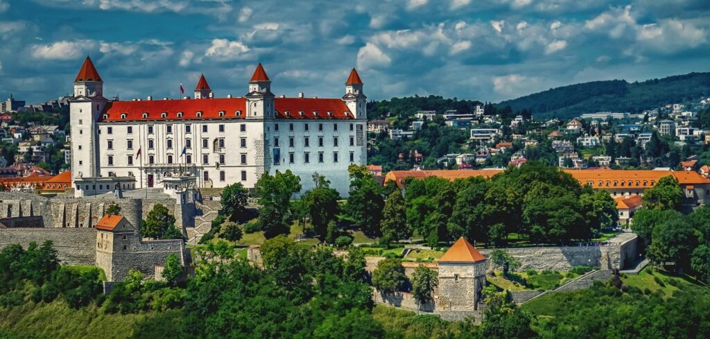 Beautiful panoramic view of Bratislava Castle towering over the Slovakian cityscape, surrounded by lush greenery.